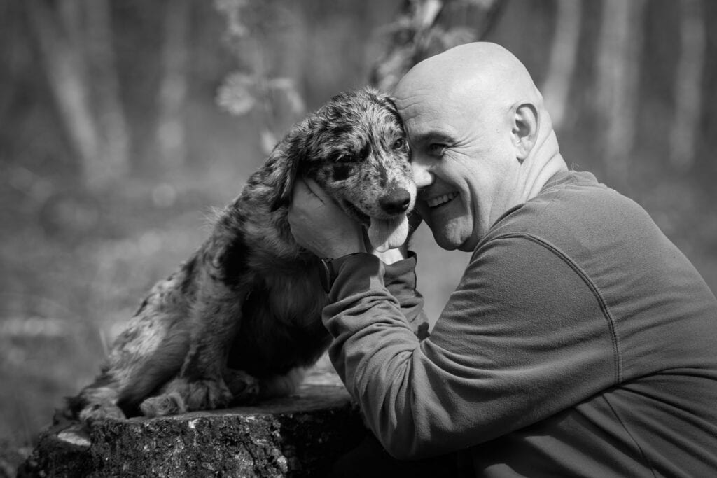 Hund og eier som leker i skogen, viser vennskap og glede.