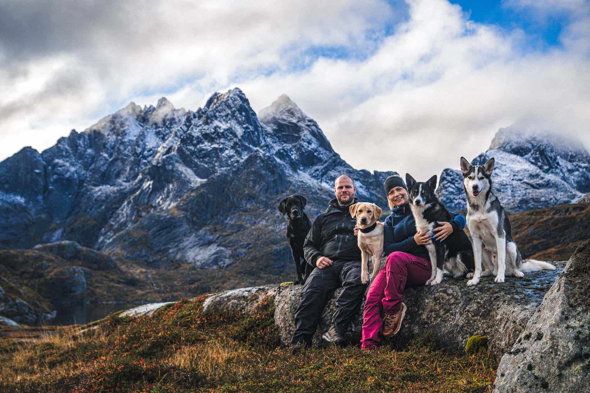 Familiefotografi med familie og hunder i naturskjønt fjellområde.