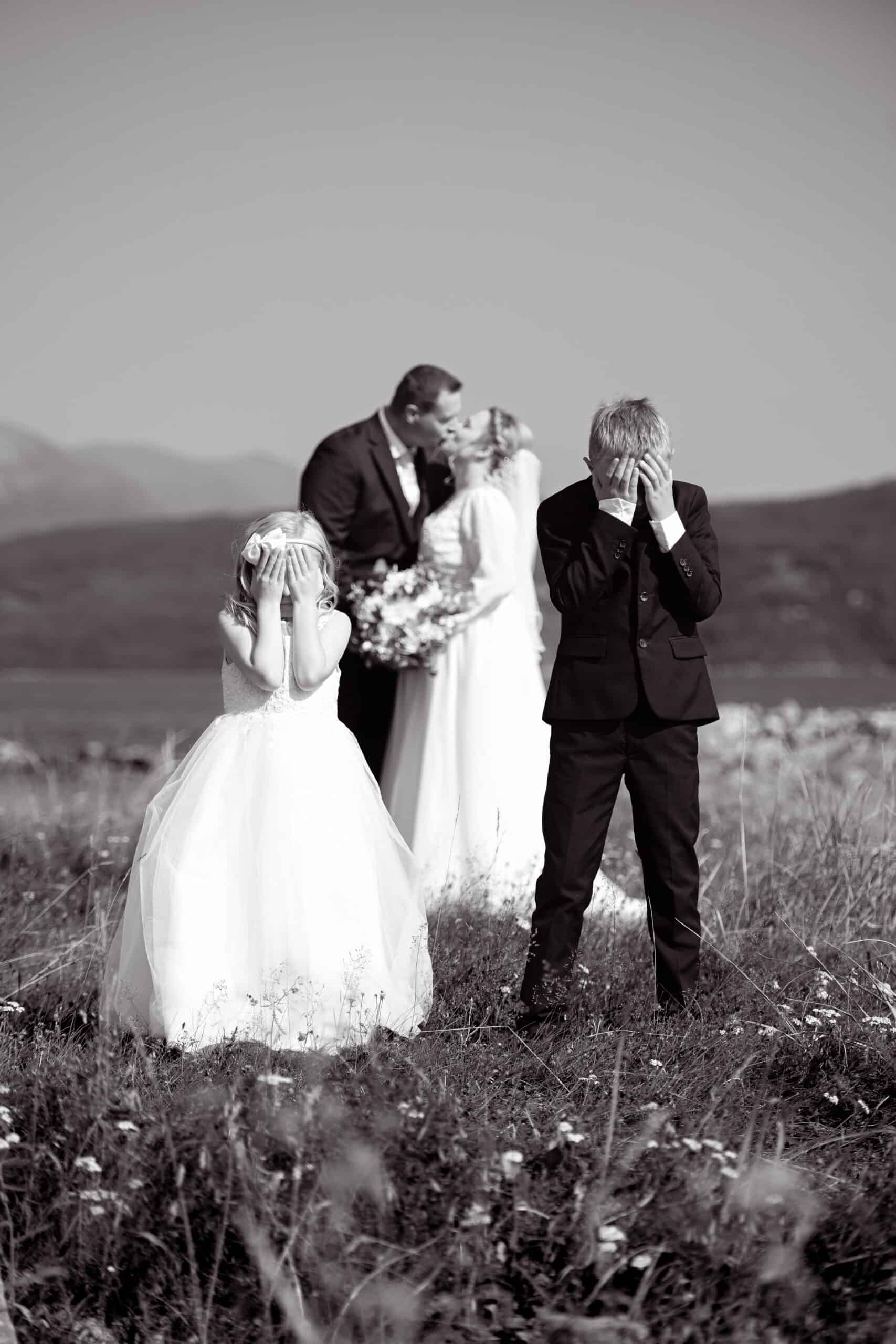 Bryllupsfotografering med par og barn i utendørs landskap.